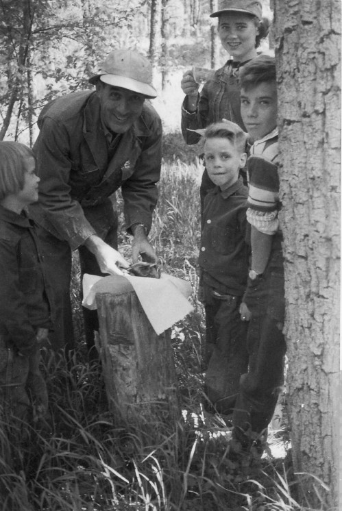 Dad with some of his kids in 1956. I think he had just caught a fish and was preparing to clean it. I'm the one leaning against the tree.