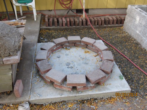 Here I am building a ring of re-purposed paver stones on top of the concrete foundation I poured.  The ring will hold a bunch of rubble (old bits of concrete from pulling old fence posts, broken cinder blocks, rocks etc) that will make a solid base for the oven.